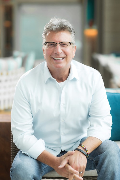 Photo of a silhouette of 2 dancers posing in front of a red curtain.